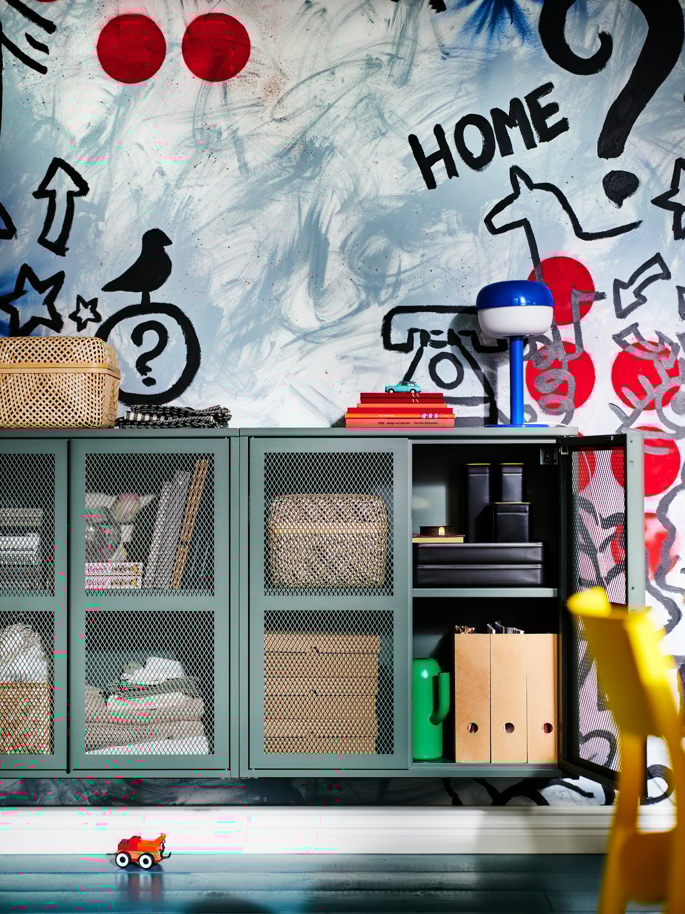 Zielone szafki metalowe IVAR wiszące na ścianie z graffiti.