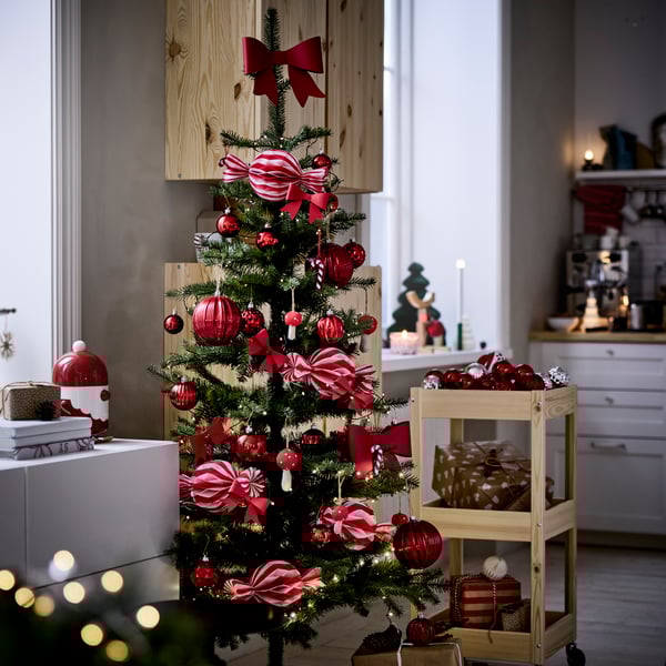 A Christmas tree is decorated with oversized candy-shaped VINTERFINT tree ornaments and red bows and baubles.