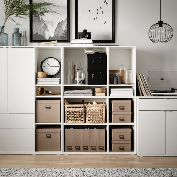 White VIHALS open shelves, storage cabinet in the living room with variou storage boxes and magazine storage box in the shelves. 