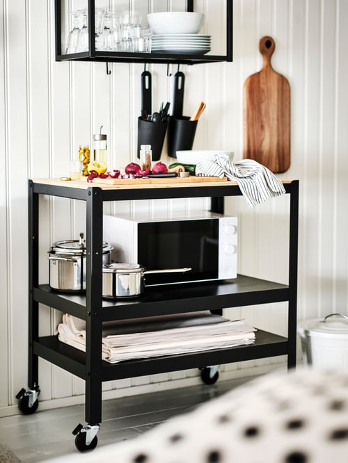 Bucătărie cu un cărucior BROR bej care susține un cuptor cu microunde TILLREDA alb și un set de 6 vase de gătit IKEA 365+ gri.