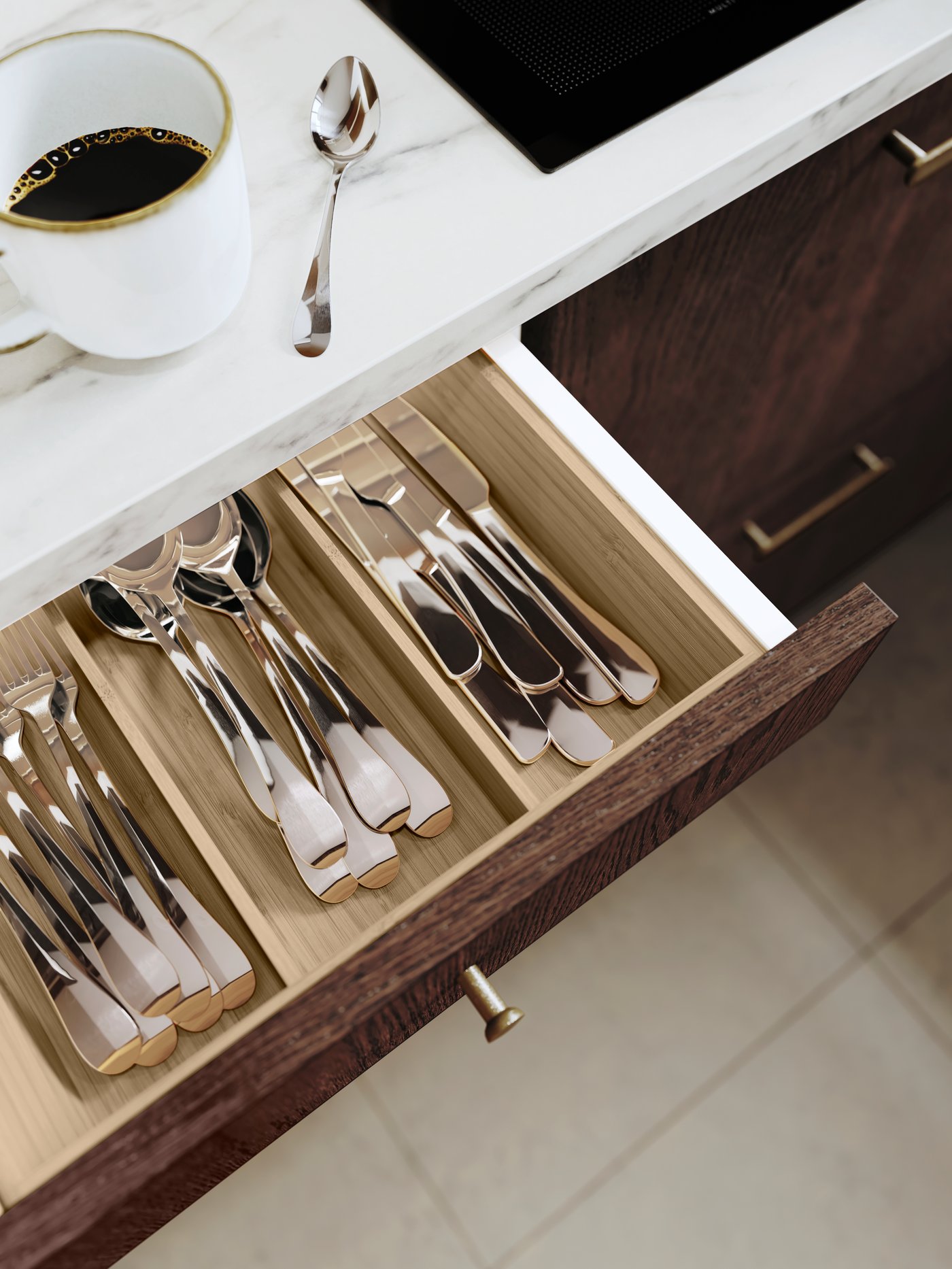 Drawers filled with knives and forks in a kitchen where you can see a cup of coffee standing on the kitchen counter.
