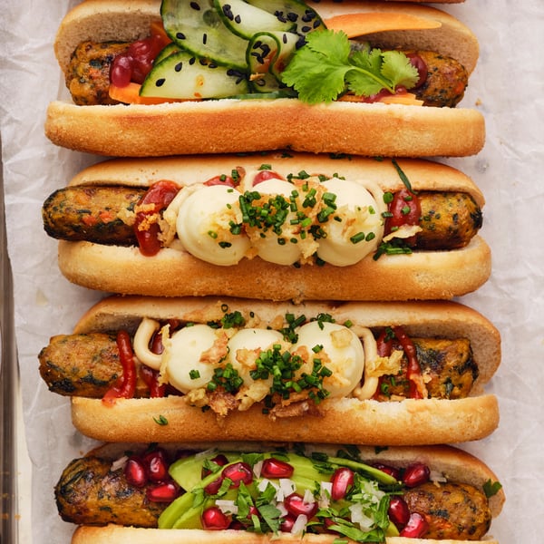 Panini con hot dog vegetariani REFRÄNG su un vassoio in metallo, guarniti con purè di patate ALLEMANSRÄTTEN e altri ingredienti.