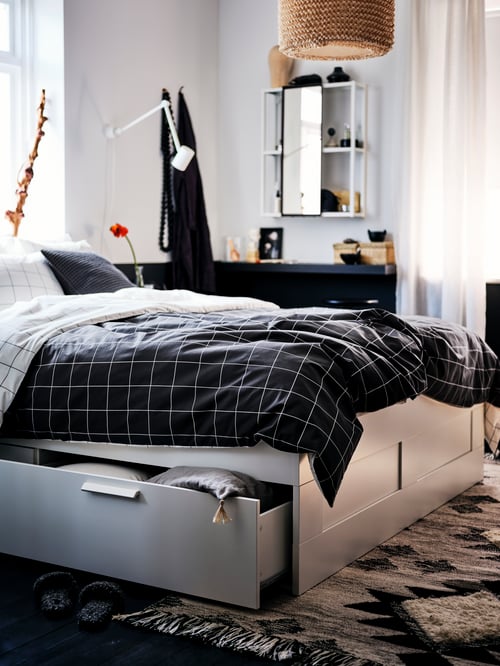 A bedroom with a white BRIMNES bed with storage made with black-and-white-chequered VITKLÖVER bed linen.