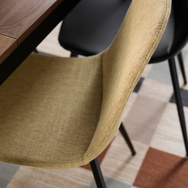 ダイニングテーブルの脇にある総布張りのNORDMANSSKÄR/ノルドマンスシェール チェア。シートシェルはリータフォルス イエローベージュ。