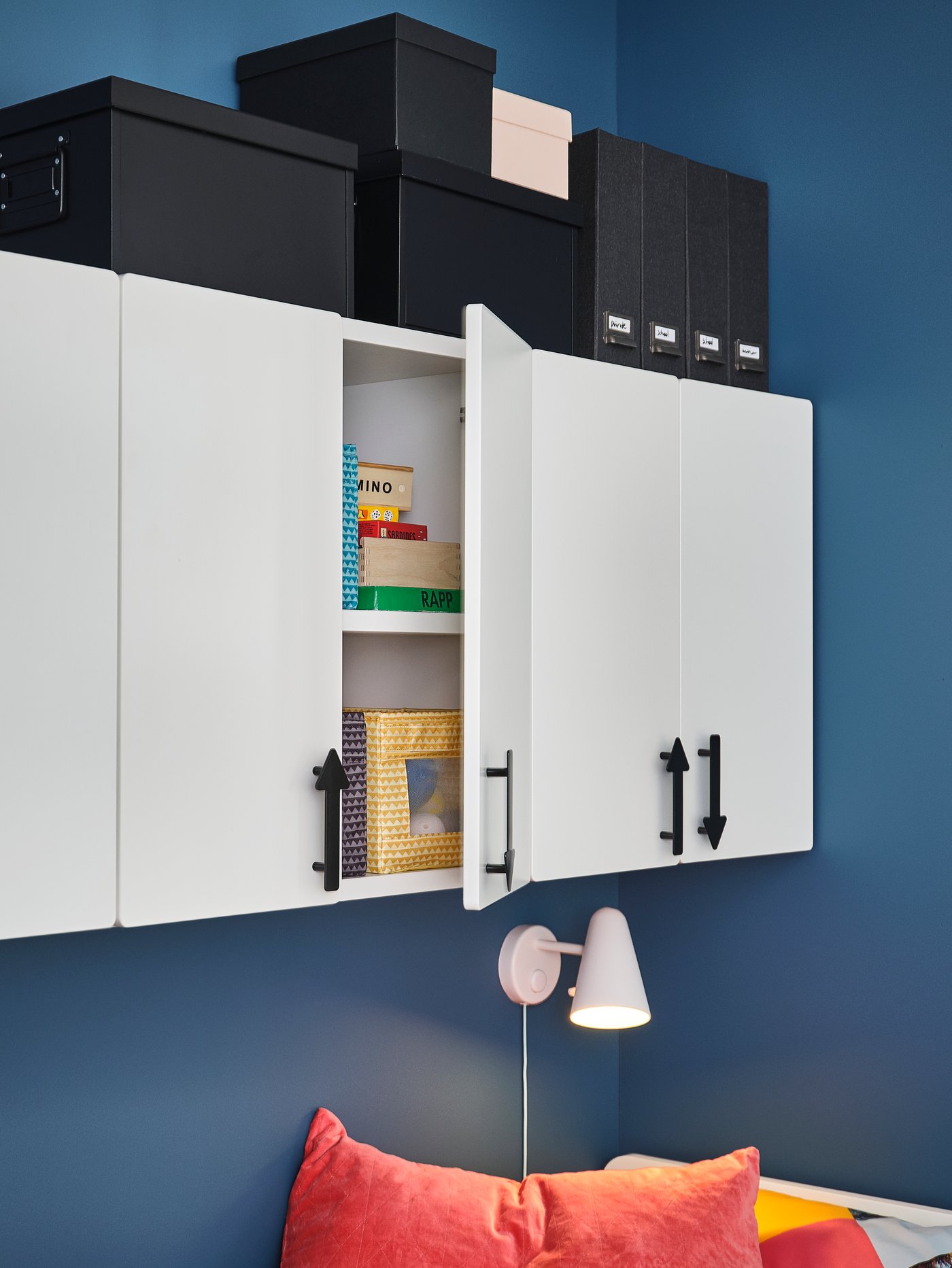 Habitación para bebés y niños con múltiples puertas blancas de tablero de fibra con tiradores negros, colocadas sobre un aplique LED blanco.