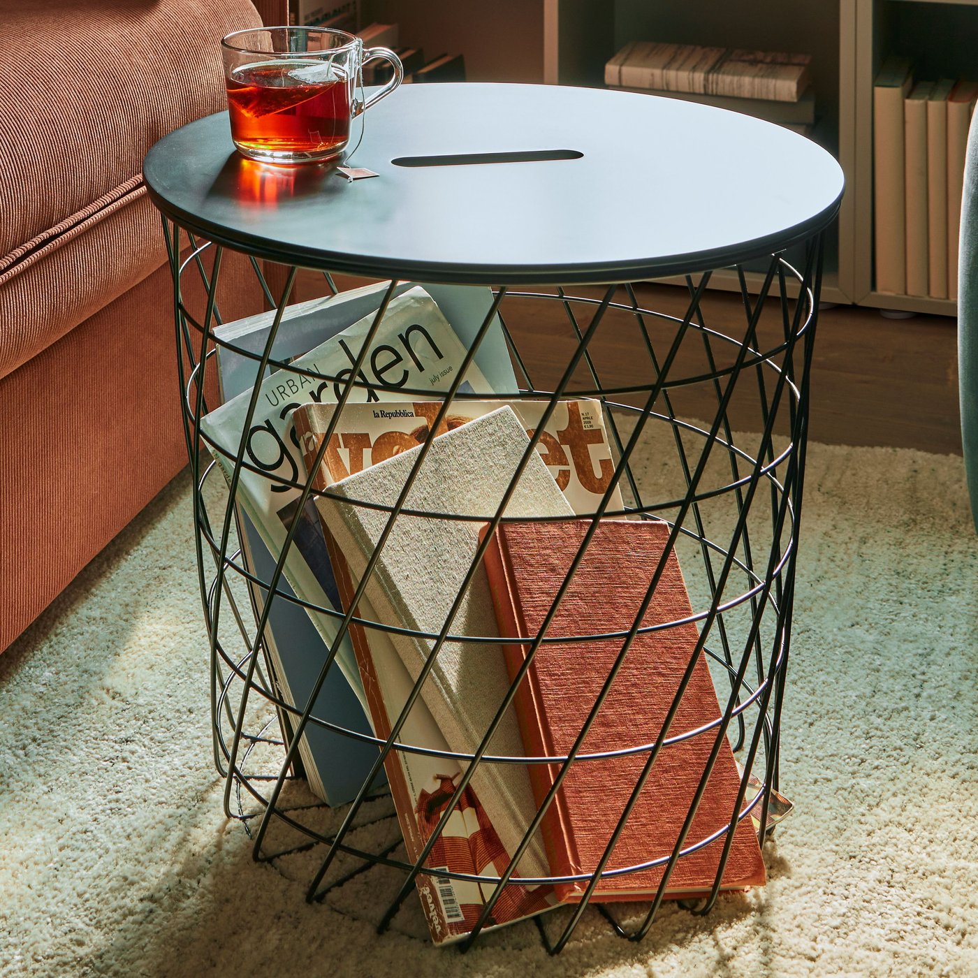 Ein KVISTBRO Aufbewahrungstisch in dem Bücher aufbewahrt werden, darauf steht eine Tasse Tee. 