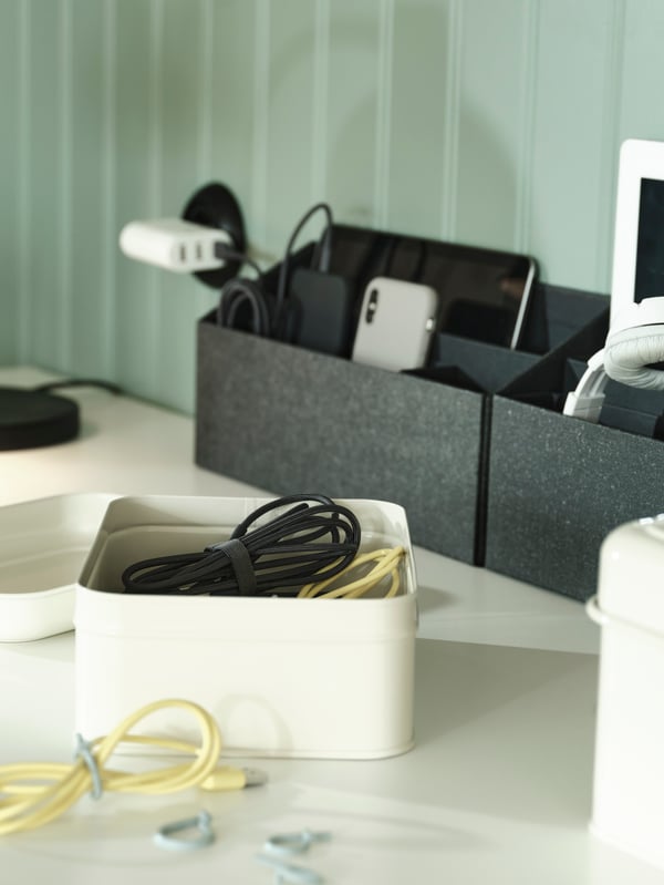 A PLOGFÅRA storage box with lid is open, showing cables neatly bundled inside. A few plastic ALFORSIT cable ties are nearby.