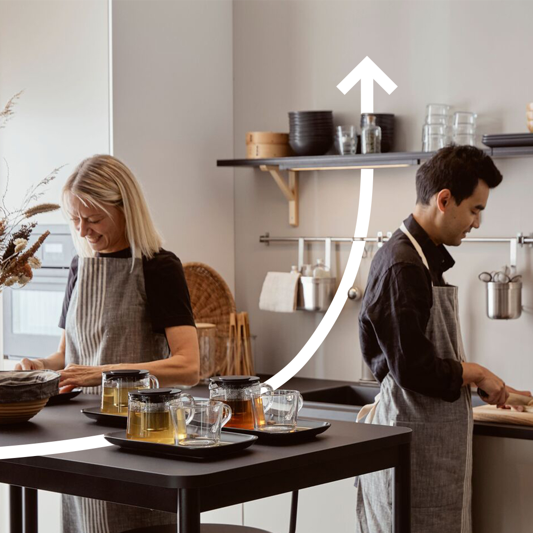 Two people handle food in a kitchen in shades of gray