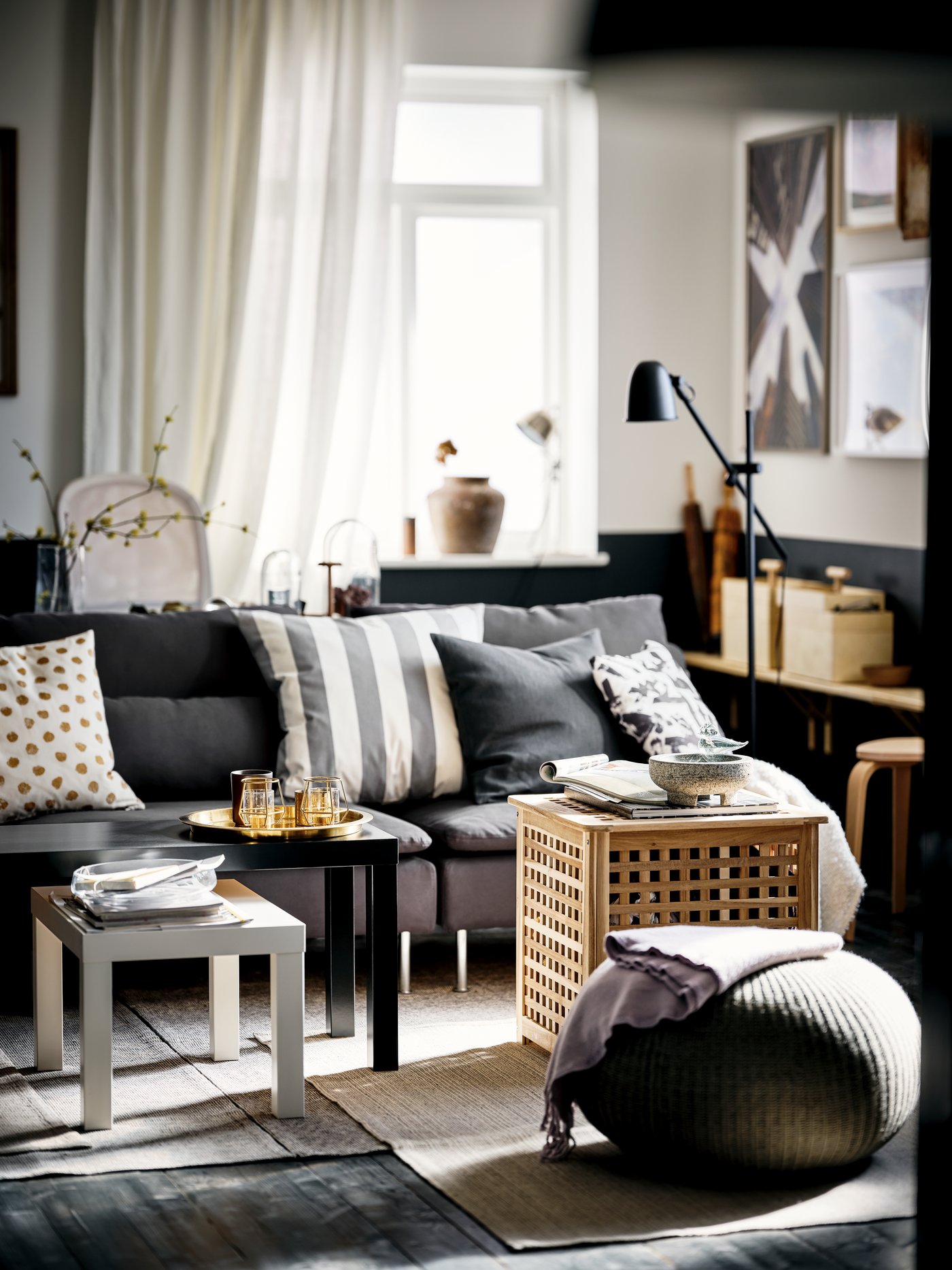 A sunlit room in a black-and-white colour scheme with black and white LACK nesting tables and a dark-grey SÖDERHAMN sofa.