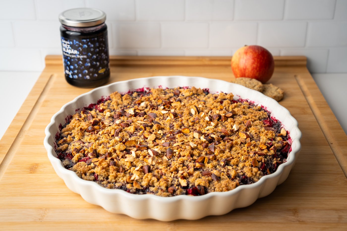 Apfel-Blaubeer Crumble in einer Auflaufform auf einem Schneidebrett präsentiert.