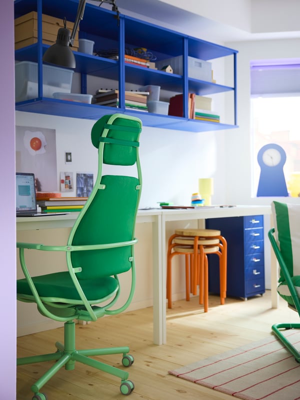 A bright green LÖPARBANA gaming chair by a desk with blue shelves on the wall behind it. Blue and orange details in back.