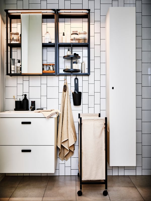 A bathroom with a GANSJÖN 3-piece bathroom set atop a washstand with an anthracite/white ENHET mirror cabinet above.