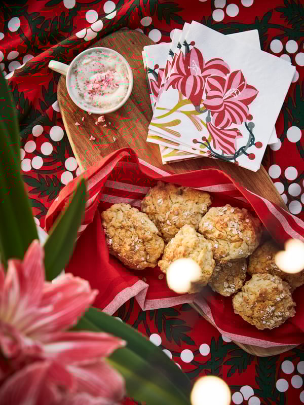Close-up of red and white patterned VINTERFINT tablecloth, paper napkins with amaryllis themed motif and scones at Christmas.