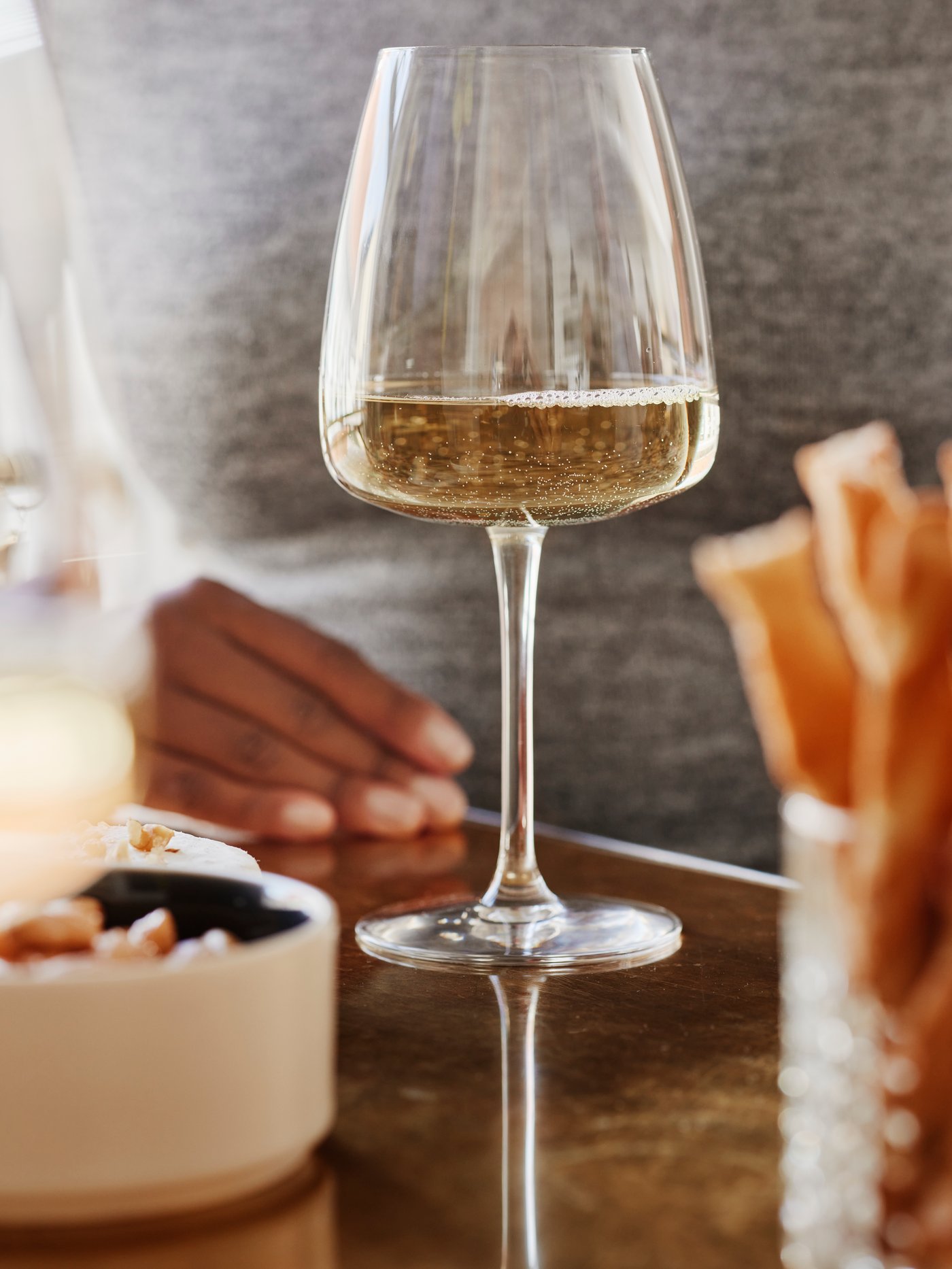 Copa de vidrio DYRGRIP junto a plato con aperitivo sobre mesa de madera.