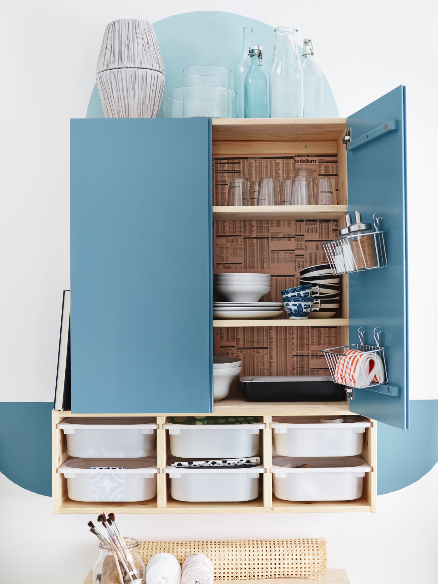 Et IVAR kabinet malet og omdannet til et spisebord med kurve fastgjort til dørene og vægopbevaring skuffer nedenunder.