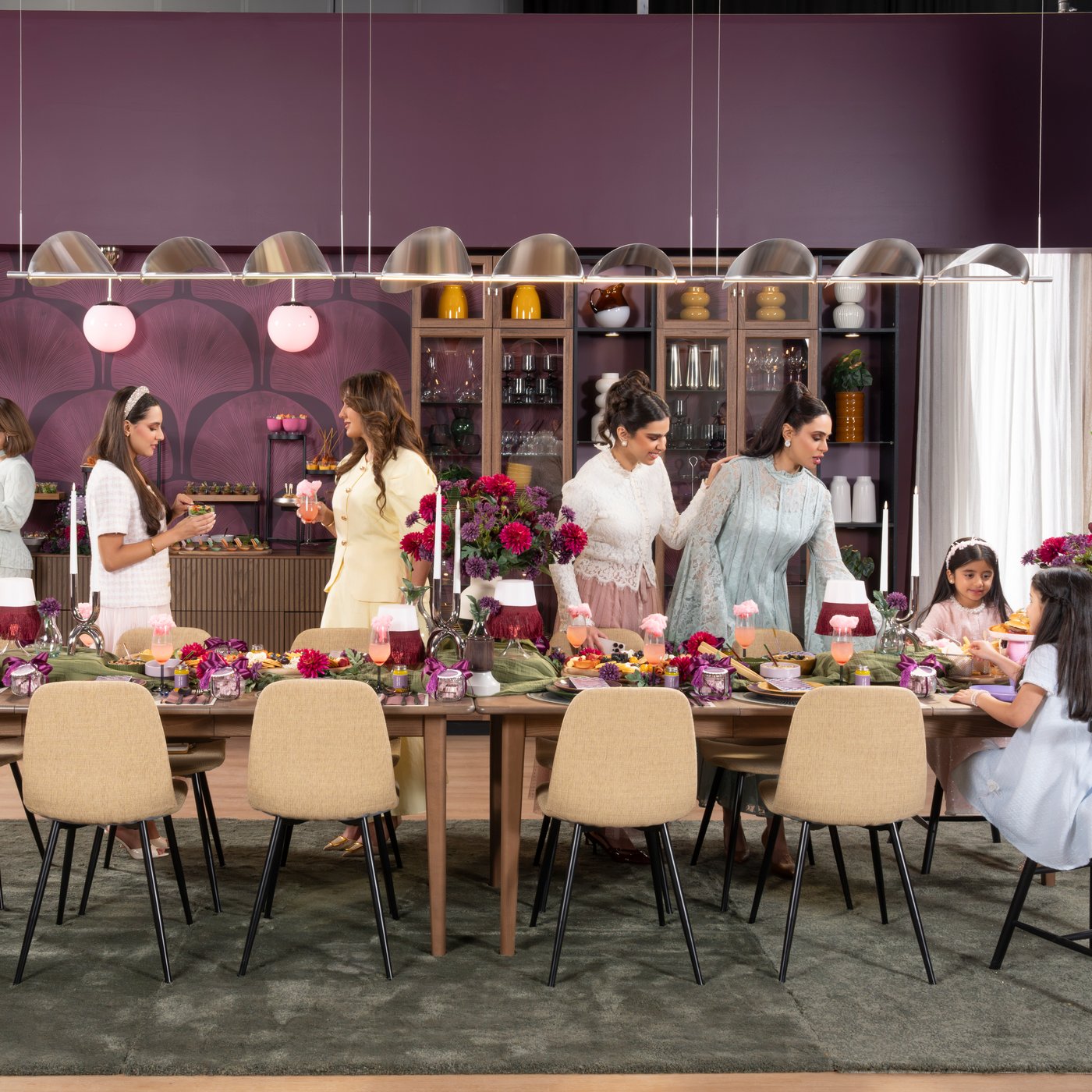 Friends gathering in a purple-themed dining room with children eating at the table.