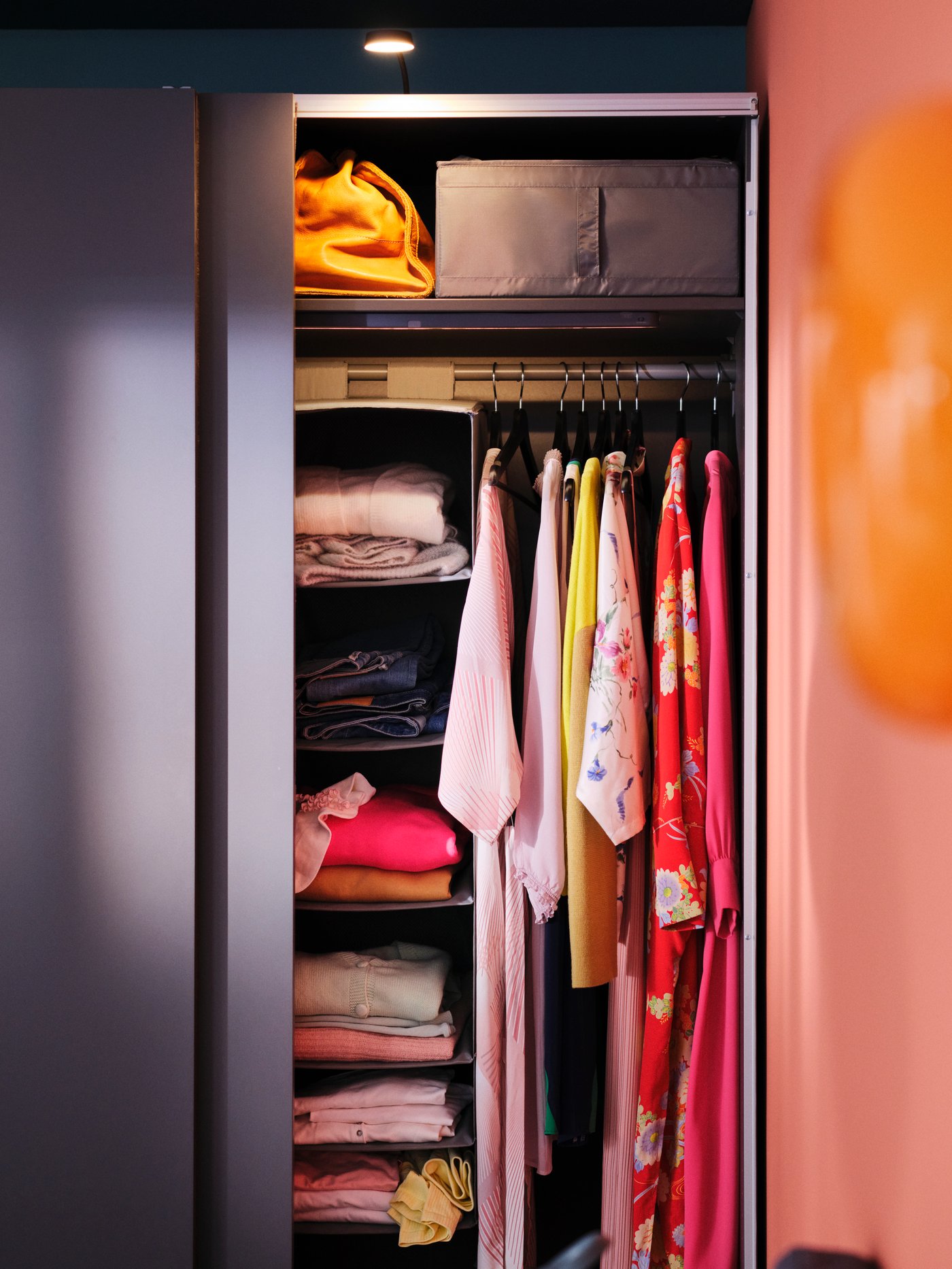 One side of a dark grey PAX/HASVIK wardrobe with the door open showing a SKUBB hanging storage with 6 compartments inside.