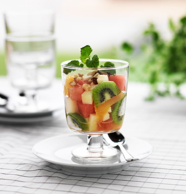 Ein frischer Obstsalat in einem IKEA 365+ Kelchglas auf einem weißen Porzellanuntersetzer.