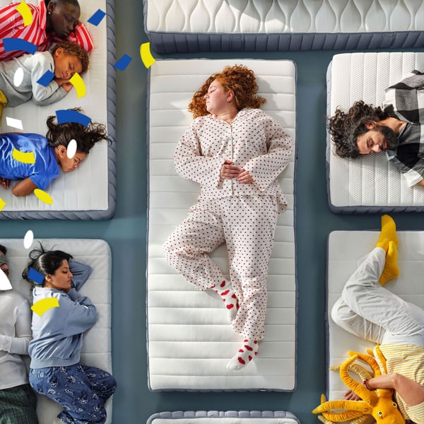 Menschen in Pyjamas liegen auf verschiedenen Matratzen in einem Ausstellungsraum – Darstellung von Schlafpositionen und Matratzenvielfalt bei IKEA.