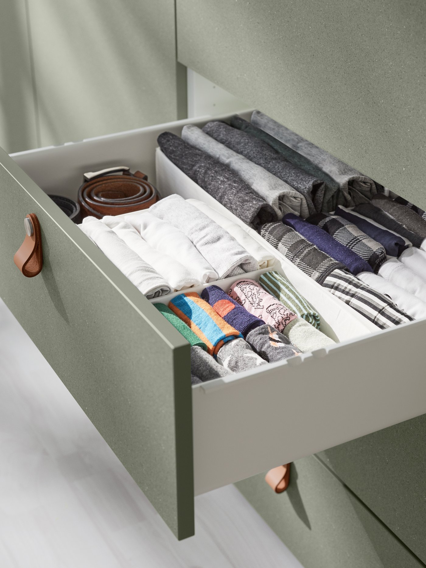 Dormitorio con una caja rectangular con compartimentos de poliéster reciclado colocada en un cajón con frontal gris.