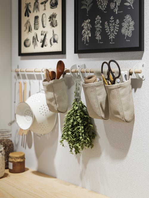Framed posters and NEREBY birch rails on a white wall, with kitchen utensils on white hooks and in hanging NEREBY containers.