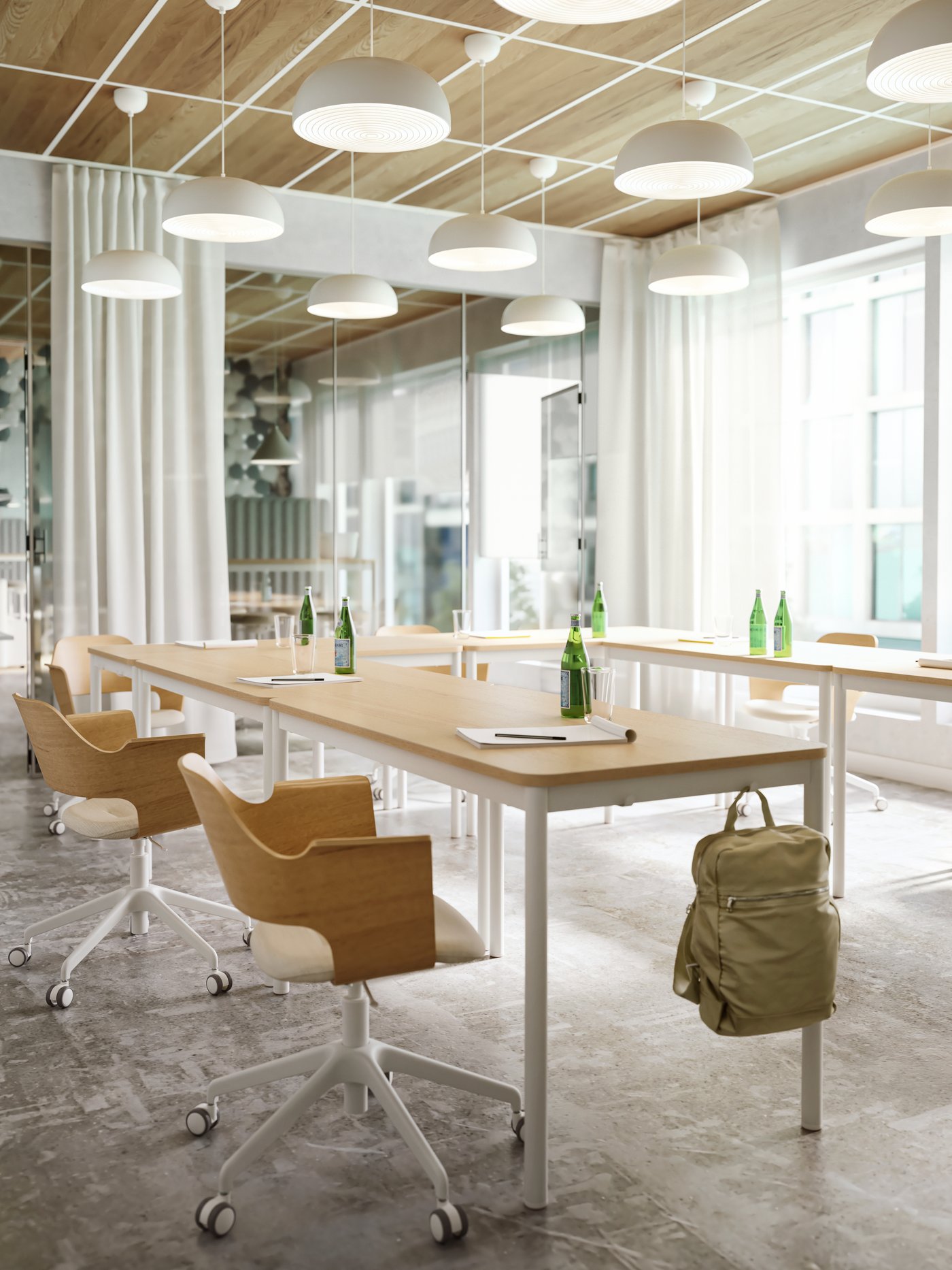 Chaises en bois clair, lampes blanches et tables en bois clair avec crochets sur le côté sur lequel un sac à dos vert est suspendu.