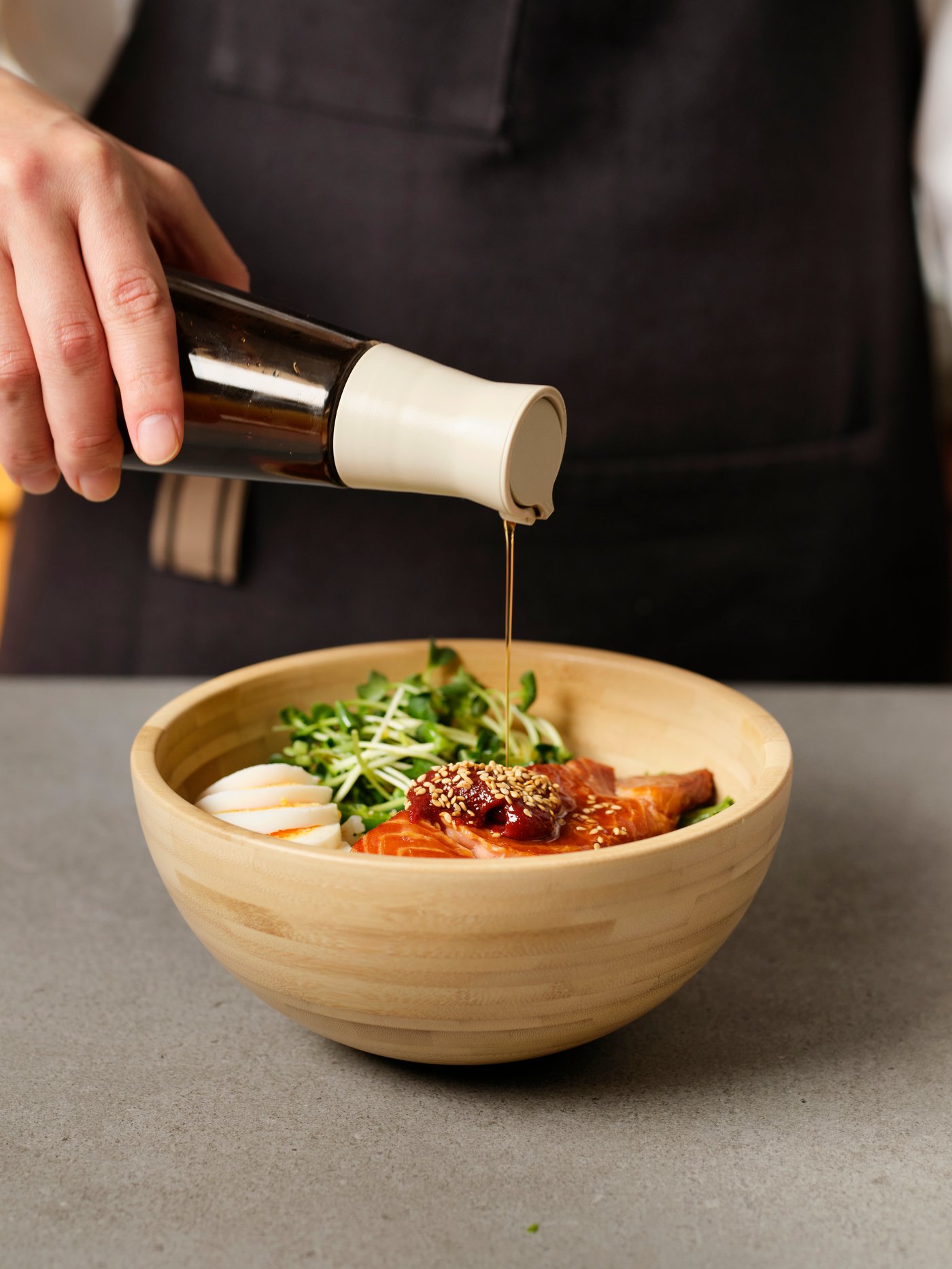 서빙볼에 담긴 재료 위로 참기름을 뿌리는 컷