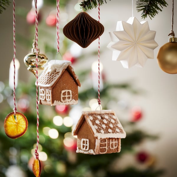 Two iced VINTERSAGA mini gingerbread houses hanging from string with various VINTERFINT tree ornaments.