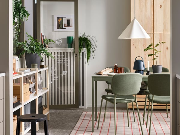 VIHALS chairs stand at a green VIHALS extendable table on a rug underneath a white ZEBRASÄV pendant lamp in a dining room.