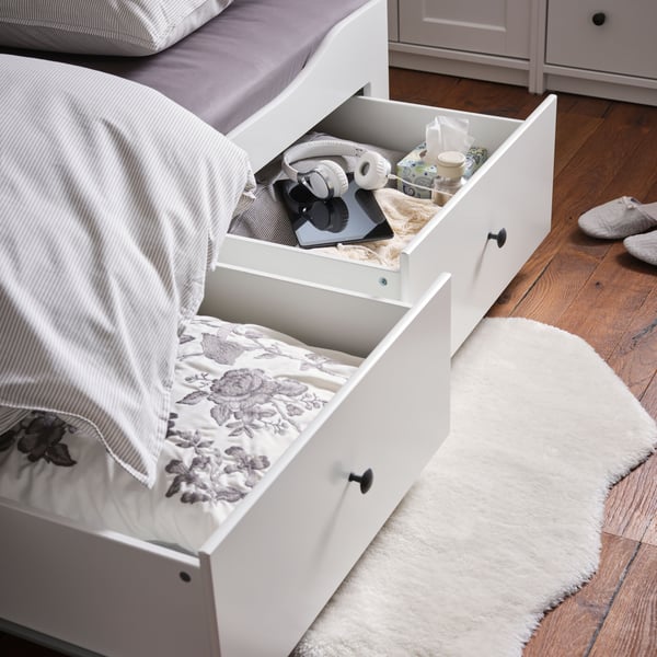 Tappeto TOFTLUND sul pavimento sotto due cassetti aperti di un letto divano HEMNES con 3 cassetti/2 materassi.