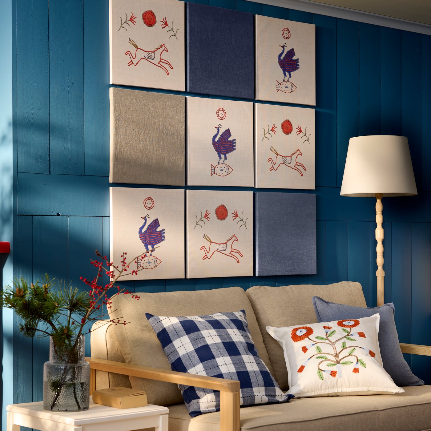 A TORNSBORG 2-seat sofa-bed in Naggen beige/pine is placed in a room with blue walls adorned with several PJÄTTERYD pictures.