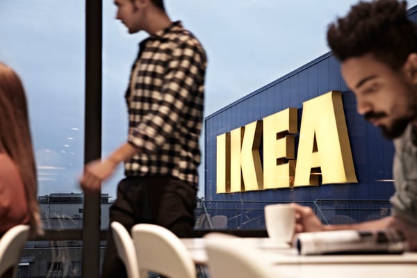 Several people in the IKEA restaurant with the store name in the background.