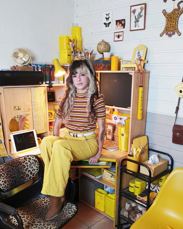 Caroline sitzt auf ihrem Schreibtisch überall gelbe Wohnaccessoires. 