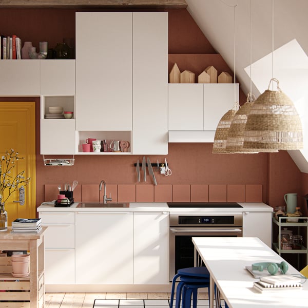 A studio apartment with large industrial-style windows, dark terracotta-coloured walls and white VALLSTENA kitchen fronts