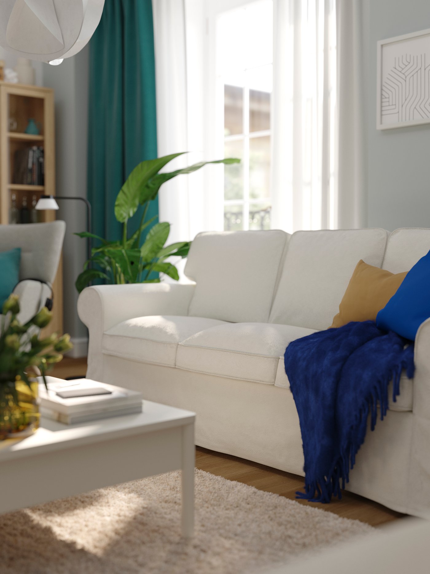 An UPPLAND sofa, with a throw and some extra cushions on it, stands in a sunny living room near a large window.