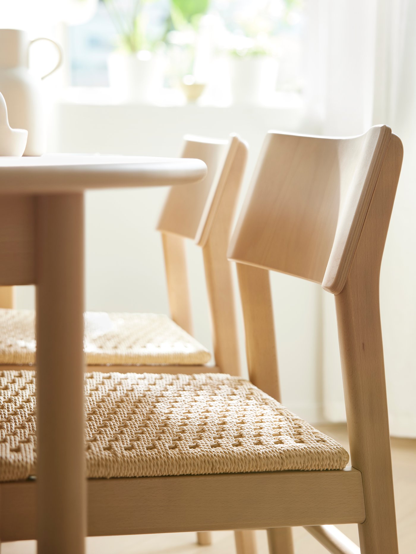 Two light beech SKANSNÄS chairs stand at a light beech/veneer SKANSNÄS round extendable table in a sunny dining room.