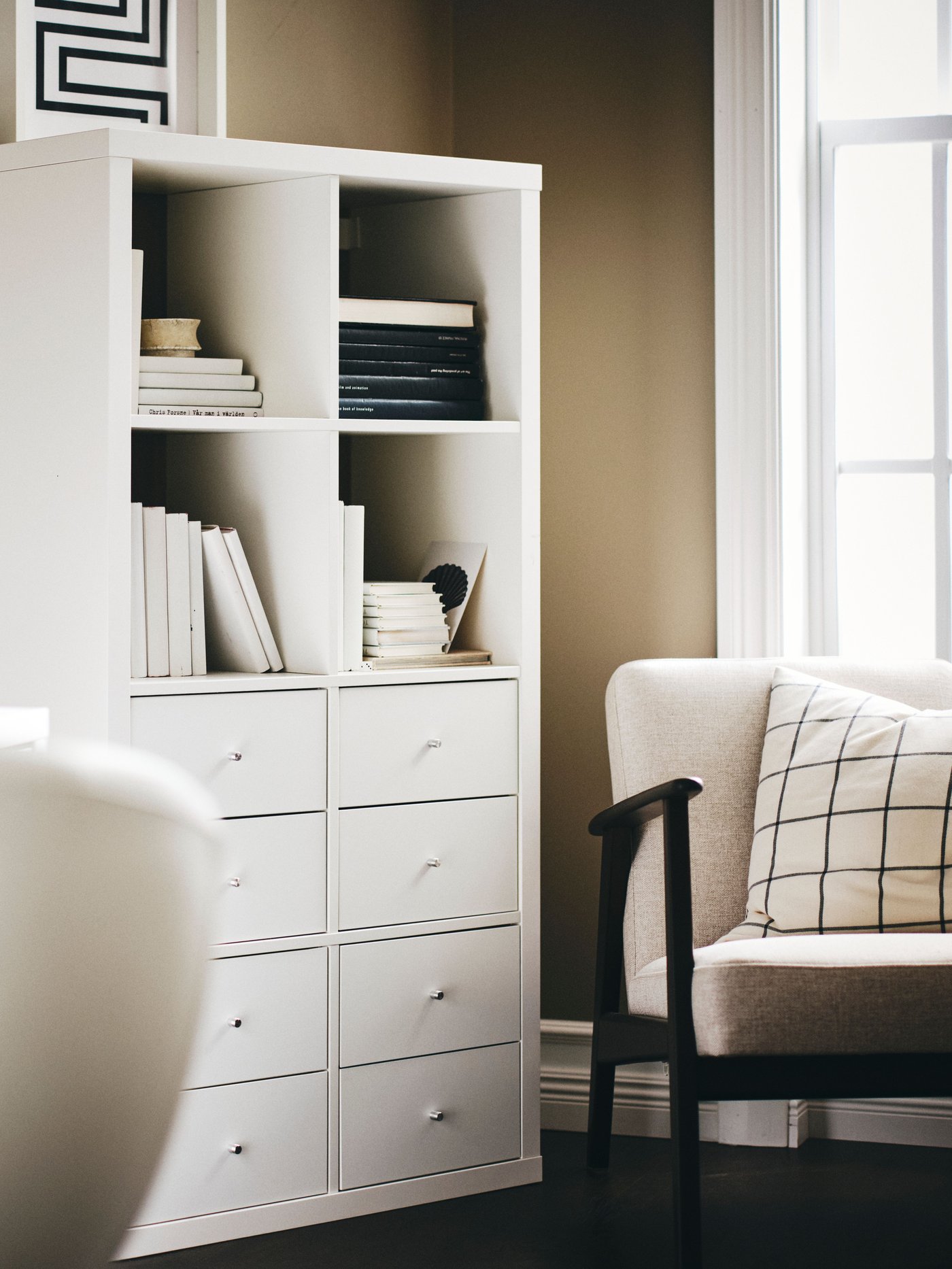 Un estante KALLAX blanco con cajnes en la parte inferior y en los espacios superiores libros y documentos organizados