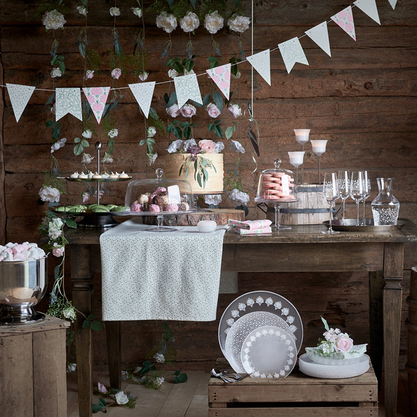 Taula dolça en tons pastels amb garlandes i un pastís al centre