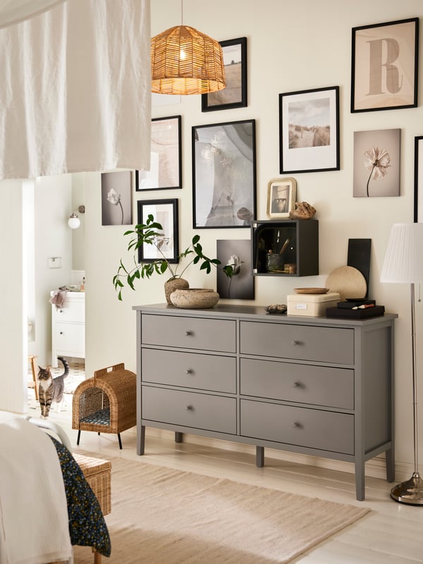 A grey GULLABERG chest with 6 drawers with a plant and various objects on top and an UTSÅDD cat house on legs beside it.