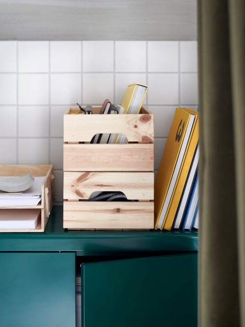 Spațiu de lucru modern prim-plan al unei cutii dreptunghiulare din pin masiv, lângă o tavă pentru scrisori, deasupra unui dulap verde.
