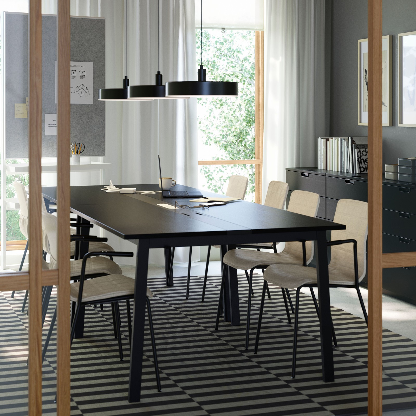 A modern meeting room with four black MITTZON conference tables, six LÄKTARE chairs in light wood and a striped wool rug.
