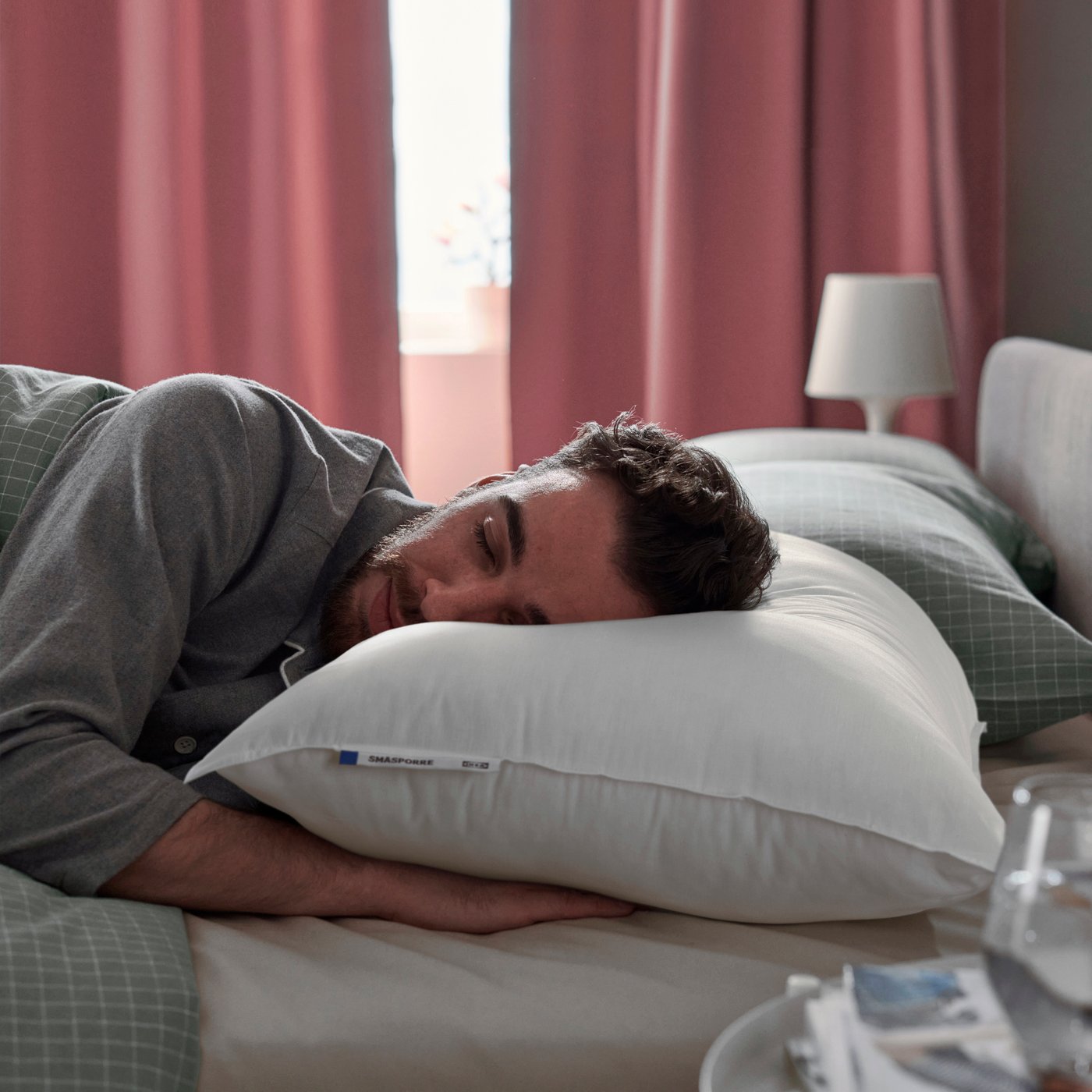 Ein Mann liegt entspannt und schlafend auf einem SMÅSPORRE Kissen in 70x90cm. 