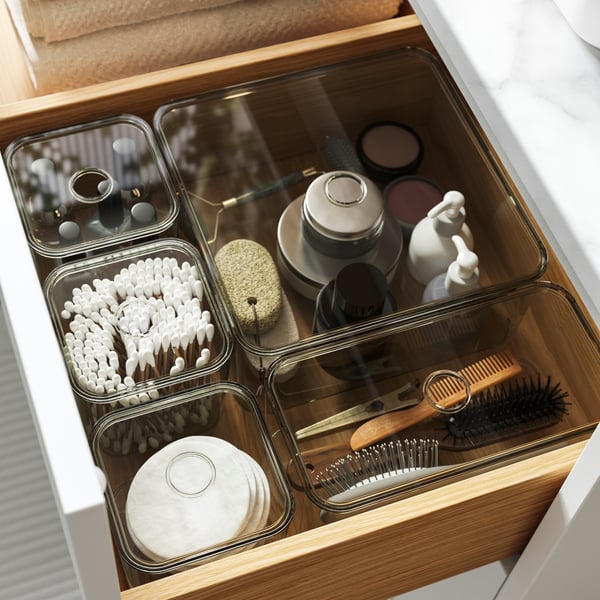 A white bathroom cabinet with an open drawer filled with VISSLAÅN 
organisers and toiletries.