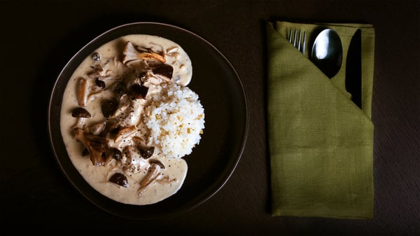 クリームソースのスウェーデンミートボールとライスを盛り付けたの一皿と、緑のナプキンに包んだカトラリー