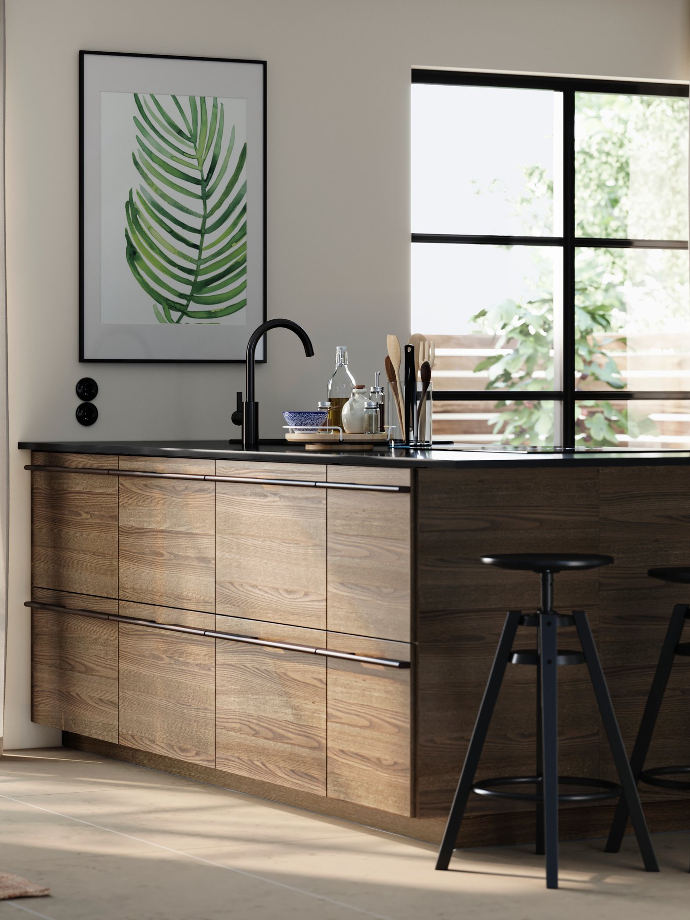 A kitchen island with STENSTA dark brown ash veneer fronts, complemented by bar stools and a large plant print on the wall.