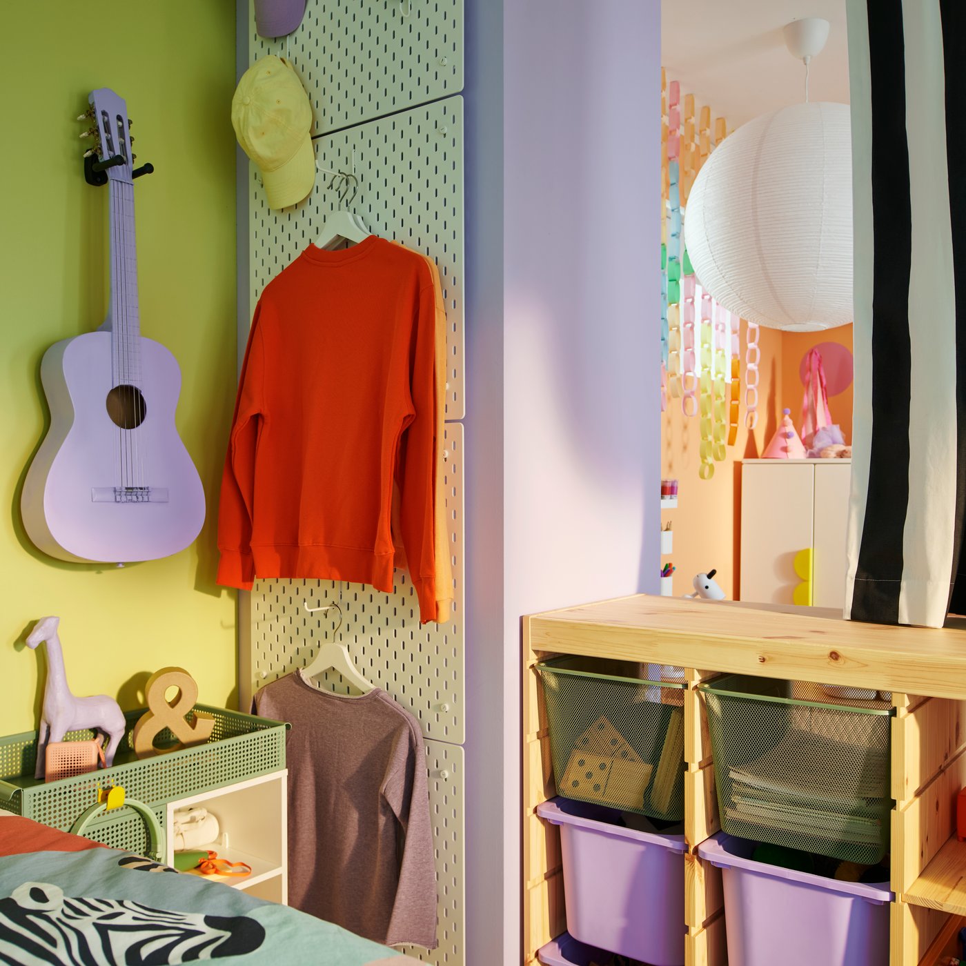 A TROFAST room divider with an open black and white stripe curtain above it next to a column of four white SKÅDIS pegboards.