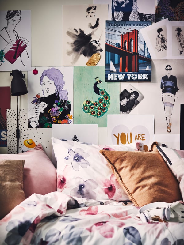 A bed dressed in a LAPPNYCKLAR duvet cover and pillowcase, with a wall covered in illustrations and BILD posters.