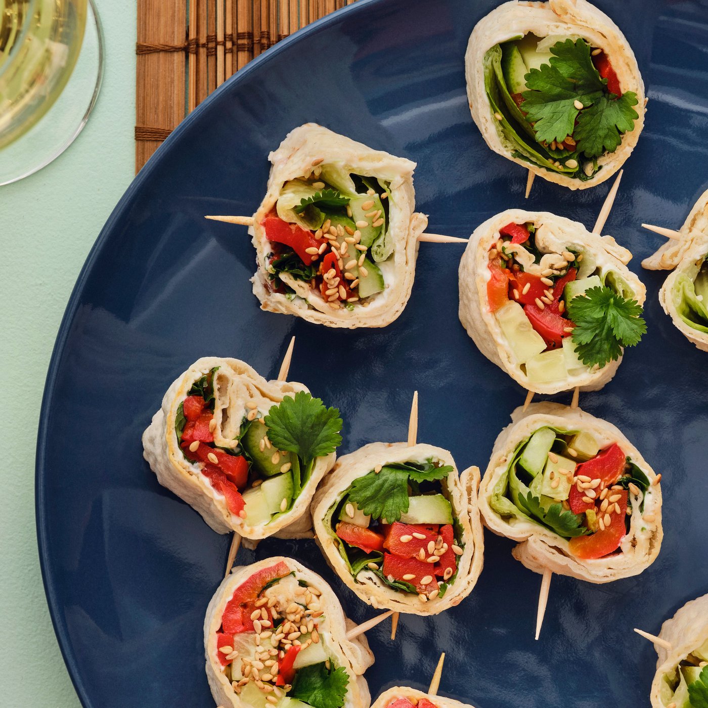 A plate featuring fresh vegetable rolls made with GRÄDDAT soft thin flatbread, garnished with green leaves and red peppers.