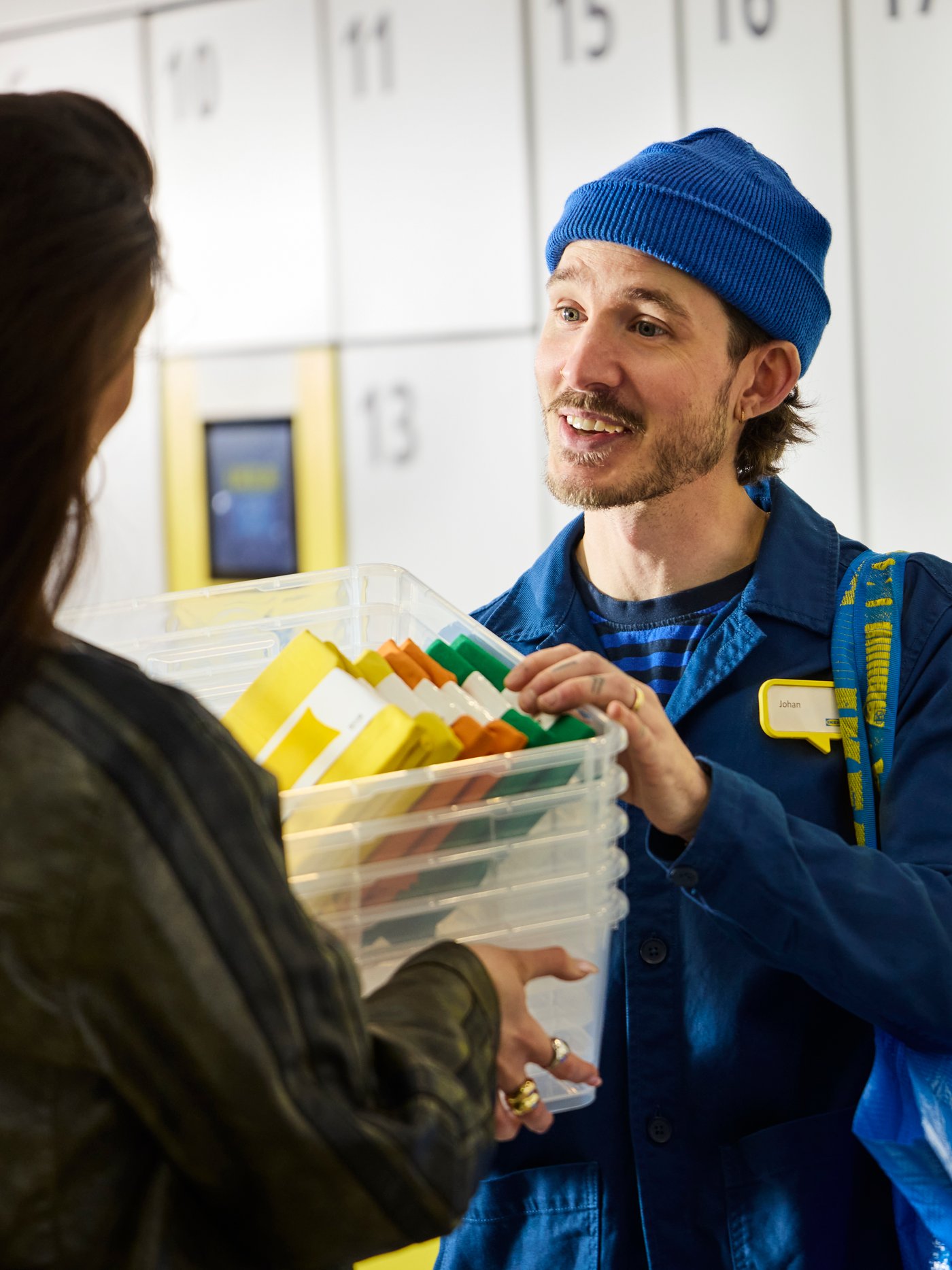 Hymyilevä IKEA-työntekijä luovuttaa IKEA-tuotteita asiakkaalle Click & Collect -noutopisteellä.