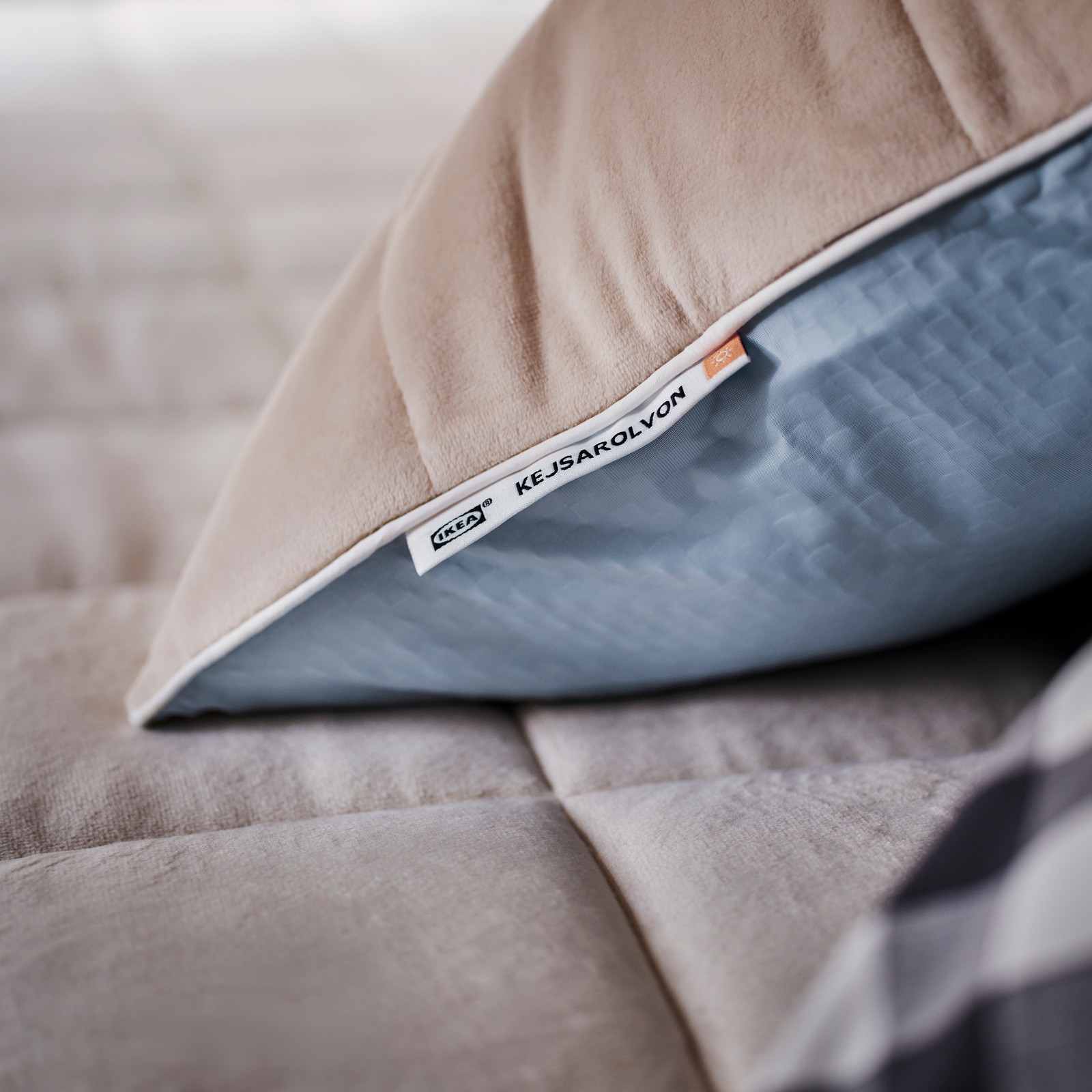 Close-up of KEJSAROLVON pillow protector with the beige side for warmth facing up and the cooling blue side down.